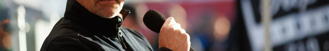 Man speaking into a microphone with a blurred background